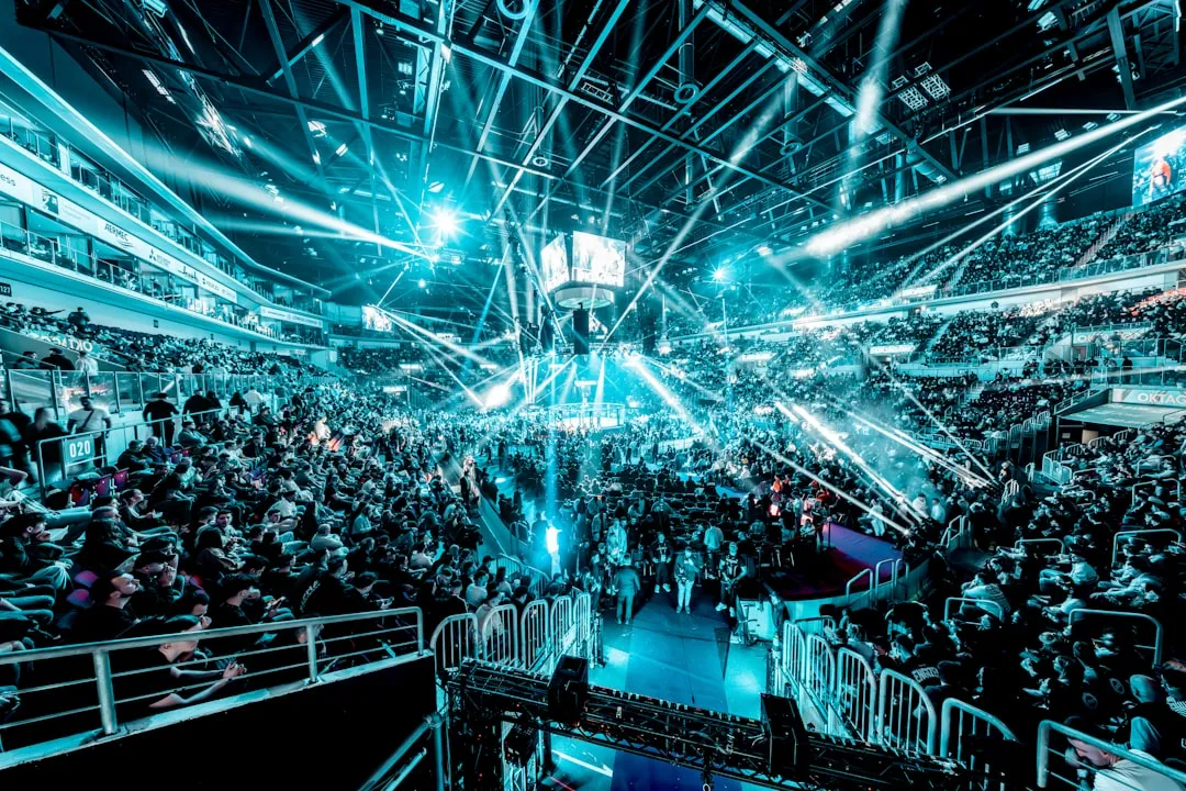 Esports arena crowd shot featuring a central stage and blue lighting, photo by Kai Kuczera on Unsplash