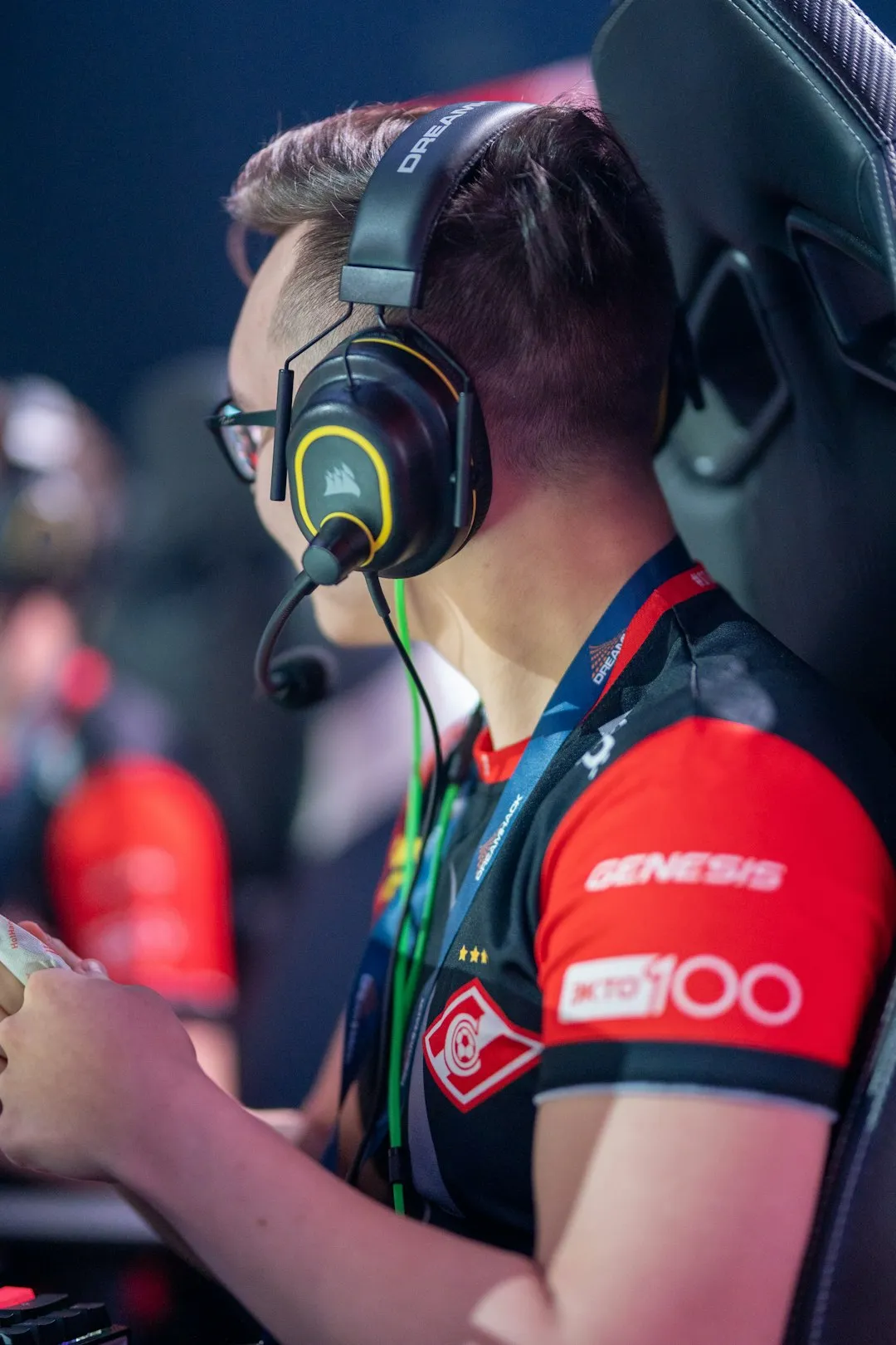 A CS:GO player wearing a Corsair headset at a DreamHack tournament, side profile, jersey with sponsor branding